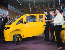 Prime Minister Justin Trudeau, third right, is shown a Veemo velomobile, a tricycle enclosed in an aerodynamic body with a built-in electric motor, at the Vancouver clean tech conference. He'll face provincial premiers later Wednesday to hammer out a climate action plan.