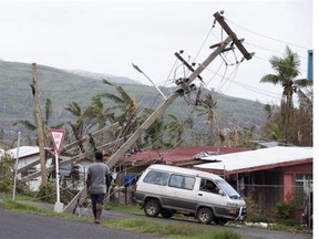 In this Feb. 24, 2016, file photo, a man walks along a street where power poles are knocked over in Rakiraki, Fiji, after cyclone Winston ripped through the island nation.