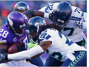 Richard Sherman #25 of the Seattle Seahawks and Michael Bennett #72 attempt to tackle Adrian Peterson #28 of the Minnesota Vikings in the first quarter during the NFC Wild Card Playoff game at TCFBank Stadium on January 10, 2016 in Minneapolis, Minnesota.