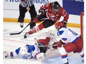 Canada's Marie-Philip Poulin sails over Russia goaltender Maria Sorokina after scoring the seventh goal as Russia's Olga Sosina(18) looks on during third period action at the women's world hockey championships in Kamloops, B.C. on Tuesday, March 29, 2016. Canada won the game 8-1.