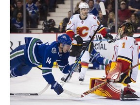 Vancouver Canucks #14 Alexandre Burrows flies through the air in front of Calgary Flames goalie Jonas Hiller in the first period of a regular season NHL hockey game at Rogers Arena, Vancouver, February 0 2016.