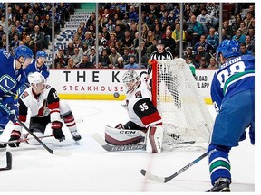Alexandre Burrows #14 of the Vancouver Canucks and Michael Stone #26 of the Arizona Coyotes eye the puck in front of Louis Domingue #35 of the Coyotes during their NHL game at Rogers Arena January 4, 2016 in Vancouver, British Columbia, Canada. (Photo by Jeff Vinnick/NHLI via Getty
