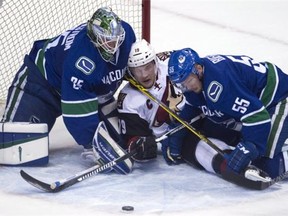 Alex Biega #55 watches Jacob Markstrom #25 of the Vancouver Canucks make a save on Shane Doan #19 of the Arizona Coyotes during their NHL game at Rogers Arena March 9, 2016 in Vancouver, British Columbia, Canada.