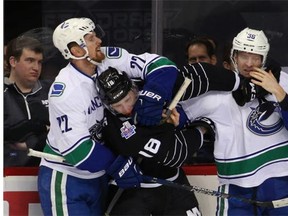 A trainer examines Vancouver Canucks center Henrik Sedin (33) of Sweden in the first period of an NHL hockey game against the New York Islanders in New York, Sunday, Jan. 17, 2016. Sedin did not return to the game.