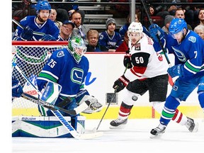Linden Vey #7 of the Vancouver Canucks and Antoine Vermette #50 of the Arizona Coyotes eye the loose puck in front of Jacob Markstrom #25 of the Canucks during their NHL game at Rogers Arena January 4, 2016 in Vancouver, British Columbia, Canada.