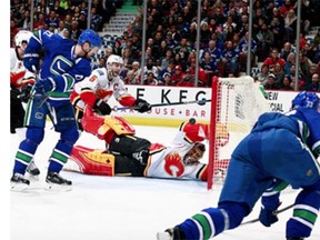 Jonas Hiller #1 of the Calgary Flames makes a save on a shot by Henrik Sedin #33 of the Vancouver Canucks as Daniel Sedin #22 of the Canucks and Mark Giordano #5 of the Flames watch during their NHL game at Rogers Arena February 6, 2016 in Vancouver, British Columbia, Canada.