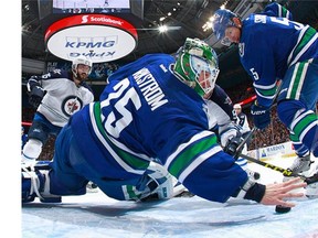 Jacob Markstrom #25 of the Vancouver Canucks reaches back with his bare hand to make a save as Mathieu Perreault #85 of the Winnipeg Jets and Luca Sbisa #5 of the Canucks watch during their NHL game at Rogers Arena March 14, 2016 in Vancouver, British Columbia, Canada.