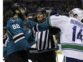 An official separates Vancouver Canucks' Alex Burrows, right, from San Jose Sharks' Brent Burns (88) during the third period of an NHL hockey game Saturday, March 5, 2016, in San Jose, Calif.