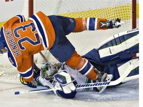 Vancouver Canucks' goalie Jacob Markstrom (25) is knocked over by Edmonton Oilers' Matt Hendricks (23) during third period NHL action in Edmonton on Friday, March 18, 2016.