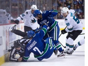 Linesman Brad Lazarowich, left, collides with Vancouver Canucks' Dan Hamhuis (2) as Linden Vey (7) digs for the puck against San Jose Sharks' Chris Tierney (50) and Roman Polak (46), of the Czech Republic, during first period NHL hockey action, in Vancouver on Sunday, Feb. 28, 2016.