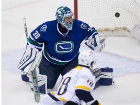 Vancouver Canucks' goalie Ryan Miller allows what proved to be the winning goal to Nashville Predators' James Neal, bottom, during third period NHL hockey action, in Vancouver on Tuesday, Jan. 26, 2016.
