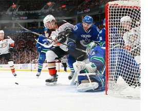 Christopher Tanev #8 of the Vancouver Canucks checks Rickard Rakell #67 of the Anaheim Ducks while Ryan Getzlaf #15 of the Ducks eyes the puck in front of Jacob Markstrom #25 of the Canucks during their NHL game at Rogers Arena January 1, 2016 in Vancouver, British Columbia, Canada. (Photo by Jeff Vinnick/NHLI via Getty Images)