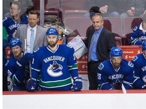 Vancouver Canucks head coach Willie Desjardins, centre, and assistant coach Glen Gulutzan, left, stand on the bench behind Henrik Sedin, of Sweden, from left, Chris Higgins, Emerson Etem and Sven Baertschi, of Switzerland, during the third period of an NHL hockey game against the San Jose Sharks in Vancouver, B.C., on Tuesday March 29, 2016.