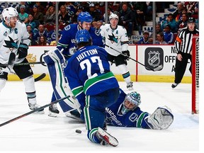 Joe Pavelski #8 of the San Jose Sharks watches as Ryan Miller #30 of the Vancouver Canucks reaches back to make a save in front of Ben Hutton #27 and Derek Dorsett #15 of the Canucks during their NHL game at Rogers Arena February 28, 2016 in Vancouver, British Columbia, Canada. San Jose won 4-1.