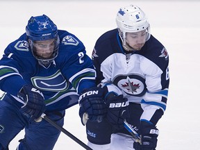 Dan Hamhuis (left) battles Alexander Burmistrov for the puck when the Canucks met the Jets March 14 at Rogers Arena.