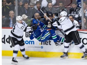 Vancouver Canucks' Andrey Pedan, centre, is checked by Los Angeles Kings' Drew Doughty, right, and Dustin Brown, left, during the second period of an NHL hockey game in Vancouver, B.C., on Monday April 4, 2016.