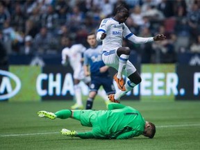 Montreal Impact's Dominic Oduro, top, of Ghana, leaps over Vancouver Whitecaps' goalkeeper David Ousted, of Denmark, as he makes a save during first half MLS soccer action, in Vancouver on Sunday, Mar. 6, 2016.