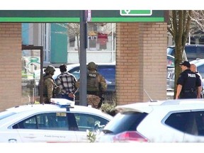 A suspect is led away from a TD Canada Trust branch in the Newton area of Surrey Tuesday afternoon after a standoff that lasted several hours and closed area roads and businesses.