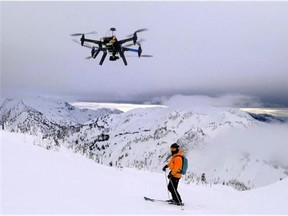 This Dec. 2014 photo shows a drone hovering by a skier as he makes his way down mountainside at resort at Revelstoke, B.C., Canada. Some US ski resorts are exploring the possibility of "drone zones" where professionally operated drones can produce customized video that show off individuals skiers in action. (Jason Soll/Cape Productions via AP)