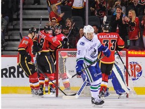 Vancouver’s Derek Dorsett skates away as the Flames celebrate Josh Jooris’s goal against the Canucks Friday night at the Scotiabank Saddledome in Calgary. The Flames won 5-2, the fourth straight game the Canucks have lost, all by the same score.