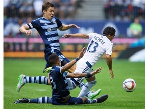 Vancouver Whitecaps’ Cristian Techara gets taken down by Sporting Kansas City’s Matt Besler, back left, and Amadou Dia during the first half of an MLS game in Vancouver last July.