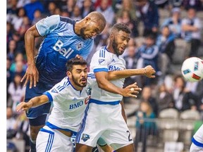 Whitecaps Kendall Waston, centre, heads the ball into the net as he collides with Montreal Impact Victor Cabrera, left, and Ambroise Oyongo, right, during the second half at B.C. Place Stadium in Vancouver on Sunday. Ric Ernst/PNG