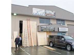 Workers repair a warehouse door damaged during a break-in at Wiser’s Wide World of Collectibles on Tuesday in Langley.