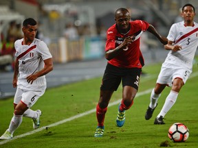 Peru's Miguel Trauco (L) vies for the ball with Daneil Cyrus (C) from Trinidad & Tobago during a friendly match at the National stadium in Lima on May 23, 2016.  / AFP PHOTO / ERNESTO BENAVIDES