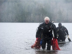 Cam Jackson, front, leads volunteers with Divers for Cleaner Lakes and Oceans out of the waters of Alice Lake with bags of garbage recovered from the lake bed.