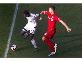 Vancouver Whitecaps' 15-year-old Alphonso Davies breaks away from Toronto FC's Eriq Zavaleta last week in Toronto. The teams go at it again on Wednesday night at B.C. Place with the Voyageurs Cup on the line.