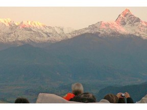 At dawn, tourists atop Sarangkot watch as sunlight bounces off the top of the peaks of the Himalayan mountains.  — Michael McCarthy