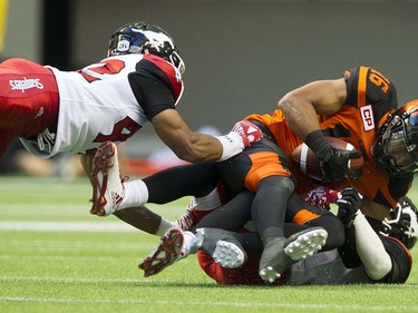 BC Lions #16 Bryan Burnham is tackled by a pair of Calgary Stampeders in a regular season CFL football game at BC Place, Vancouver June 25 2016.