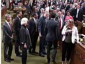 Prime Minister Justin Trudeau, with back to camera, goes across the floor to engage Thomas Mulcair in the House of Commons.