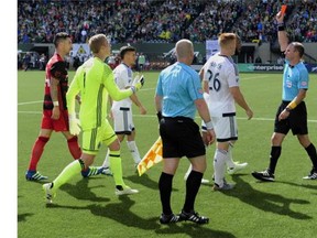Referee Ted Unkel issues a red card to Vancouver Whitecaps defender Kendall Watson as defender Tim Parker (26) looks on during the second half of an MLS Soccer game against the Portland Timbers in Portland, Ore., on Sunday, May 22, 2016. The Timbers won 4-2.