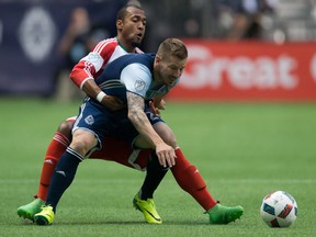 New England Revolution's Teal Bunbury, left, ties up Vancouver Whitecaps' Jordan Harvey.