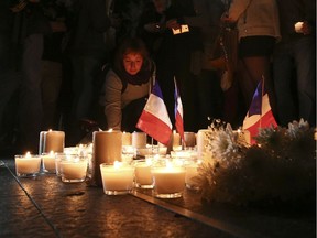 A woman places a candle during a vigil to honor victims of the Bastille Day tragedy in Nice, France, in Sydney, Australia, Friday, July 15, 2016. World leaders are expressing dismay, sadness and solidarity with France over the attack carried out by a man who drove truck into crowds of people celebrating France's national day in Nice.