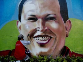 Artist Nicolay Shamanika retouches a mural of Venezuela's former president Hugo Chavez in Caracas, Venezuela in 2014. Canada's messed-up payroll system Phoenix makes one think of it was designed by Chavez, Wayne Moriarty opines.