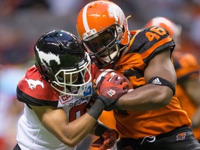 B.C. Lions Rolly Lumbala, right, is stopped by Calgary Stampeders Ciante Evans in Vancouver on June 17. But blocking is largely what Lumbala is called on for, and, at 6-foot-2-inches tall and 245 pounds, he’s physically able to handle the challenge. — The Canadian Press files