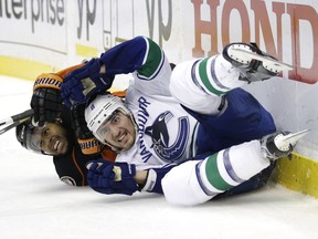 Vancouver Canucks' Chris Tanev, front, and Anaheim Ducks' Devante Smith-Pelly fall to the ice in overtime of an NHL hockey game Sunday, Dec. 28, 2014, in Anaheim, Calif. The Ducks won 2-1.