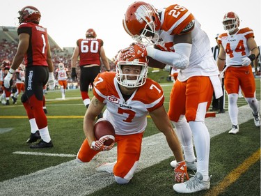 BC Lions' Eric Fraser, centre, celebrates with teammate Steven Clarke, after running in an interception for a touchdown against the Calgary Stampeders during first half CFL football action in Calgary, Friday, July 29, 2016.