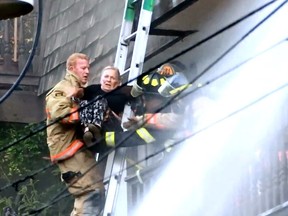 Firefighters pull a woman from the an upper unit of a North Vancouver apartment on Monday. Several people were forced to flee their home after flames and smoke engulfed the complex at St. Patrick’s Avenue and East 2nd Street. [PNG Merlin Archive]