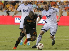 Houston Dynamo midfielder Oscar Garcia (27) dribbles around Vancouver Whitecaps defender Tim Parker (26) during the second half during an MLS soccer match Saturday in Houston. Houston and Vancouver played to scoreless draw.