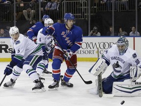 Vancouver Canucks goalie Ryan Miller and defenceman Luca Sbisa (5) defend New York Rangers left wing Chris Kreider.