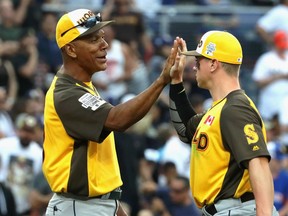 World Team manager Moises Alou (C) high fives Tyler O'Neill #4 after defeating the U.S. Team 11-3 in the SiriusXM All-Star Futures Game at PETCO Park on July 10, 2016 in San Diego, California.