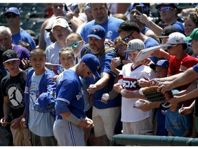 Toronto Blue Jays' Troy Tilowitzki signs autographs for fans prior to a baseball game between the Toronto Blue Jays and the Chicago White Sox in Chicago, Saturday, June 25, 2016.