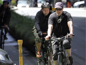 Vancouver cyclists, one with a helmet and one without, ride down the Hornby Street bike lane in 2012. One reader suggests the most useful approach is for all revenues collected from helmet-law infractions to go directly to that City of Vancouver department charged with enforcing the rules, and not to general revenues. Mark van Manen/PNG files