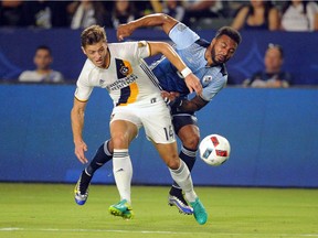 Los Angeles Galaxy forward Robbie Rogers battles with Vancouver Whitecaps FC midfielder Giles Barnes during the first half at StubHub Center in Carson, Calif.
