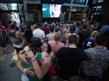 Three people embrace during a viewing party for the final stop in Kingston, Ont., of a 10-city national concert tour by The Tragically Hip, in Vancouver, B.C., on Saturday August 20, 2016. Lead singer Gord Downie announced earlier this year that he was diagnosed with an incurable form of brain cancer. THE CANADIAN PRESS/Darryl Dyck ORG XMIT: VCRD111