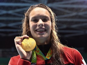 Canada's Penny Oleksiak holds up her gold medal after her first-place finish in the women's 100m freestyle finals during the 2016 Olympic Summer Games in Rio de Janeiro, Brazil, on Friday, Aug. 12, 2016.
