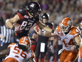 Ottawa Redblacks' Patrick Lavoie (82) jumps to keep B.C. Lions' Adam Bighill (44) and Solomon Elimimian (56) away from the ball.